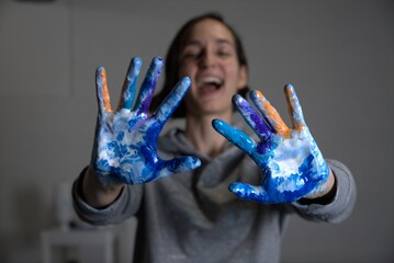 Mujer joven blanca riendo a carcajadas con las manos pintadas, una pintora