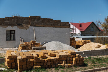 A pile of bricks lies in front of the house that is being built