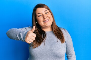 Fototapeta premium Beautiful brunette plus size woman wearing casual clothes doing happy thumbs up gesture with hand. approving expression looking at the camera showing success.