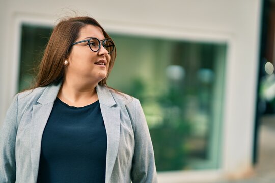 Young hispanic plus size businesswoman smiling happy standing at the city.