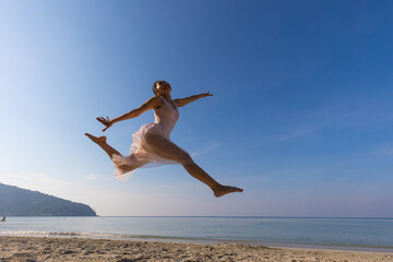 Fototapeta na wymiar Asian woman in white dress ballet dancing on the beach.