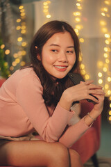 Beauty young asian woman black hair sitting on a couch holding smartphone in christmas party.