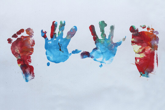 The handprints and footprints of a baby paint on a white background.