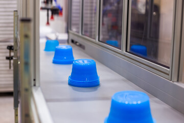 Moving polypropylene pots on conveyor belt of automatic plastic injection molding machine at...