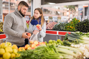 Glad couple choosing vegetables in grocery shop. High quality photo
