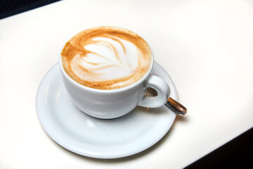 A cup of coffee. Latte with heart pattern in a white cup.