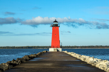 A pier leads up to the bright red Manistique Lighthouse, and landmark on the Lake Michigan coast of the Upper Peninsula of Michigan.