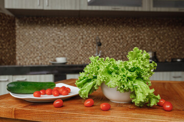  Fresh vegetables - cherry tomatoes, lettuce and cucumber on the cutting board at home kitchen. The concept of vegeterian food