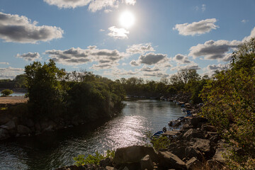 Obraz premium Boats on the river, trees, cloudy sky and sun
