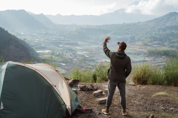 Portrait adventurous man camping captures the moment. Beautiful mountain scenery in the morning