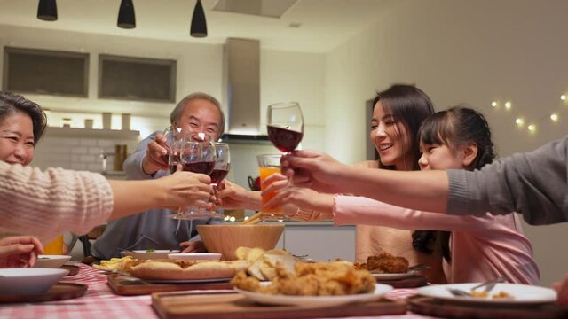 Asian big family clinking wine glasses together in the happy moment.