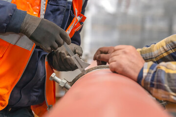 Workers are pipe fitting adjustment (fit-up) with clamps before welding.