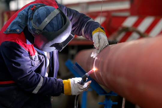 The welder is welding to root pass of the pipes with gas tungsten arc welding process in the factory.