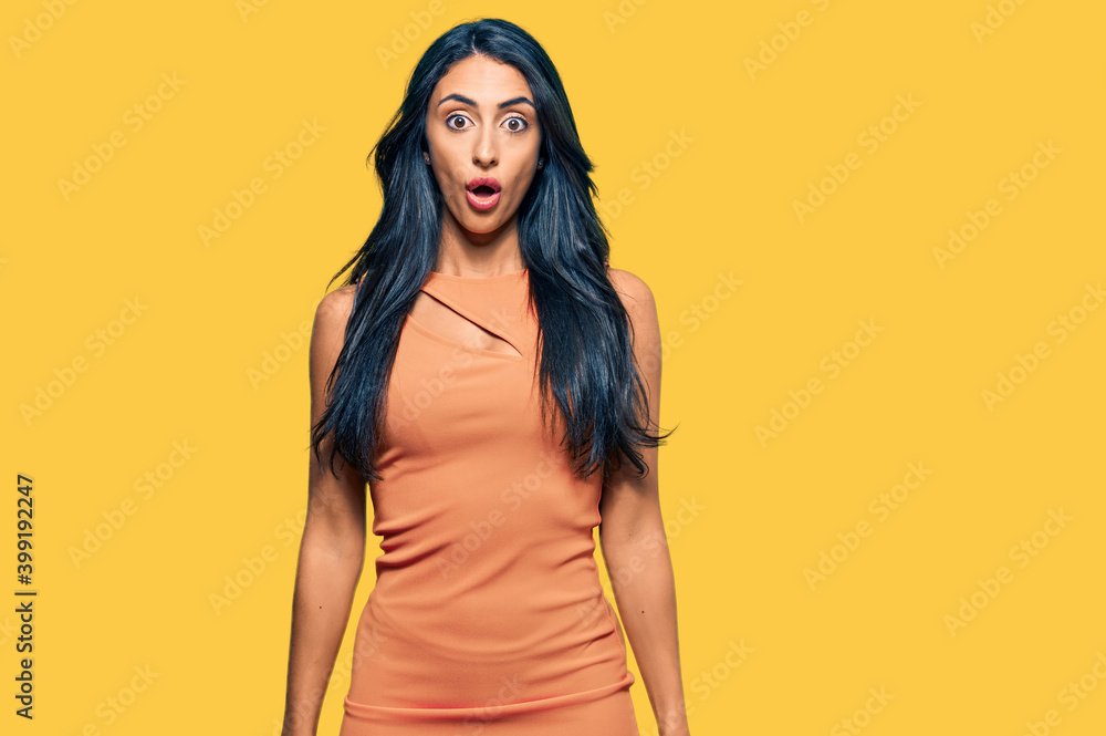 Wall mural beautiful hispanic woman wearing summer dress scared and amazed with open mouth for surprise, disbel