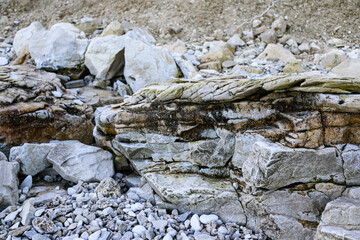 mountain textures of stones with interlayers of gypsum, colored quartz, clay, sand and other layers of various ores, with different textures, color and density, in gypsum ore quarry.