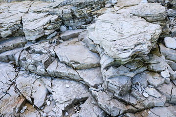 mountain textures of stones with interlayers of gypsum, colored quartz, clay, sand and other layers of various ores, with different textures, color and density, in gypsum ore quarry.