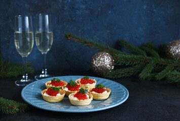 Tartlets with cream cheese and red caviar on a beautiful plate on the New Year's table. New Year's snack.