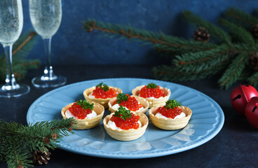 Tartlets with cream cheese and red caviar on a beautiful plate on the New Year's table. New Year's snack.