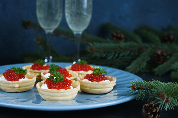 Tartlets with cream cheese and red caviar on a beautiful plate on the New Year's table. New Year's snack.
