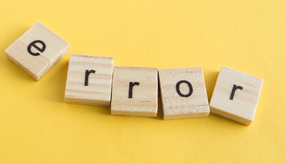 On the wooden blocks written ERROR, wooden blocks on a yellow background, top view, flat ley