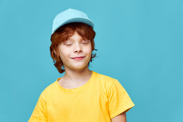 Redhead boy eyes closed blue cap yellow t-shirt