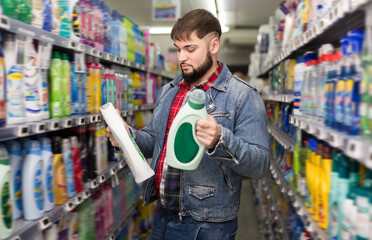 Fine young man making purchases in household chemistry store