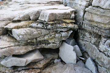 mountain textures of stones with interlayers of gypsum, colored quartz, clay, sand and other layers of various ores, with different textures, color and density, in gypsum ore quarry.