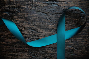 Top view of  teal ribbon on dark background with copy space. Cervical and ovarian cancer, sexual...