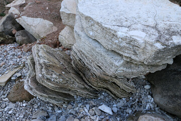 mountain textures of stones with interlayers of gypsum, colored quartz, clay, sand and other layers of various ores, with different textures, color and density, in gypsum ore quarry.