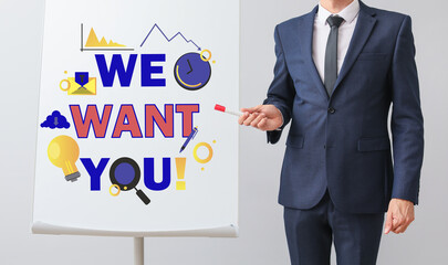 Businessman near flipchart with text WE WANT YOU on light background. Concept of career growth