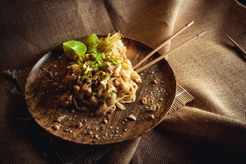 Chicken pad thai noodles with lime , mung bean sprouts and nuts on linen background
 - obrazy, fototapety, plakaty