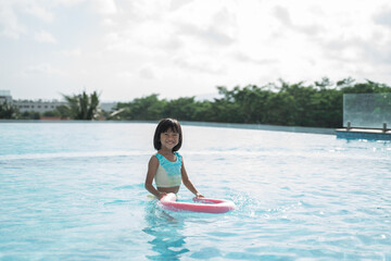Portrait little girl trying learn swimming in pool alone