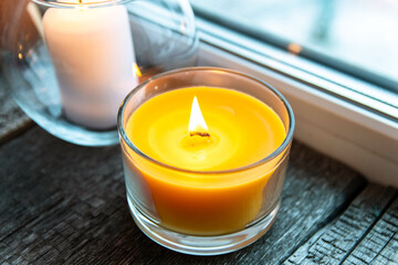 Cozy atmosphere - candles on a wooden window sill at dusk. Candles in glass candlesticks.