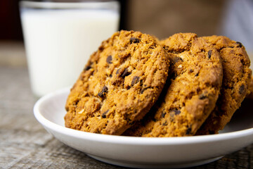Close-up of cookies on a white plate and a glass of milk on a wooden background.