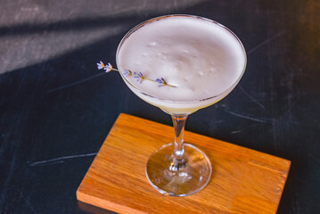 Summer cocktail in a Martini glass with fresh lavender flower. Lavander alcohol drink, refreshing beverage in restaurant