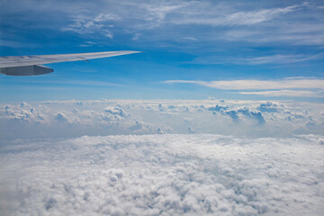 looking out the aircraft window to scenic blue sky with puffy small clouds
