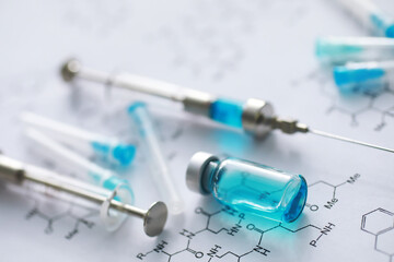 small jars with injection and syringe for injection on a blue background near the chemical formula
