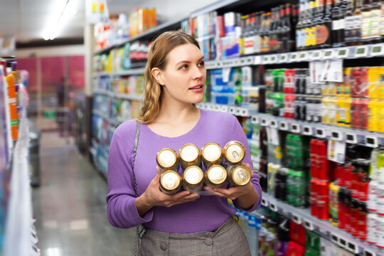 Attractive adult woman buys can beer in hypermarket