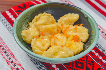 Dumplings, filled with mashed potato in plate on traditional Ukrainian tablecloth. Varenyky, vareniki, pierogi, pyrohy.