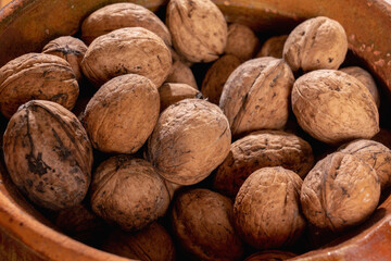 Close up dirty natural walnut background pattern texture. Abstract walnuts heap pattern background. Walnuts with shells. Horizontal image.