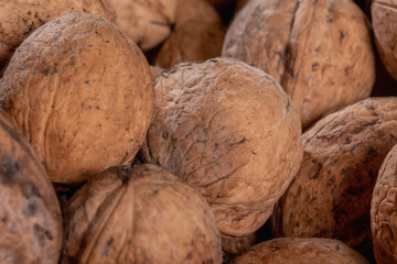 Close up dirty natural walnut background pattern texture. Abstract walnuts heap pattern background. Walnuts with shells.