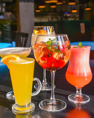 Cocktails on the table. Different coloured drinks in different glasses on dark wooden table.