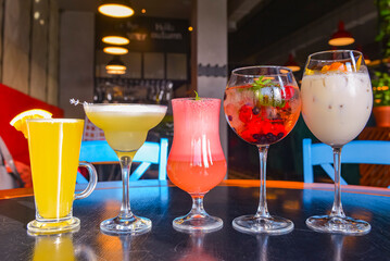 Cocktails on the table. Different coloured drinks in different glasses on dark wooden table.