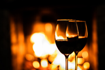 Two glasses of red wine on the background of fireplace lights