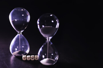 Sand running through the bulbs of an hourglass measuring the passing time in a countdown to a...