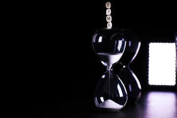 Sand running through the bulbs of an hourglass measuring the passing time in a countdown to a...
