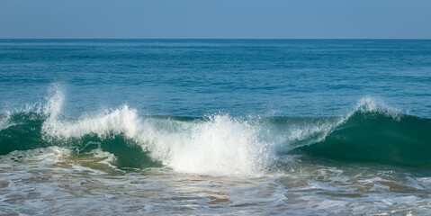 Breaking sea wave on a sandy beach background