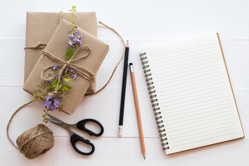 notebook with box package prepare send to customer by post office arrangement flat lay style on background white wooden