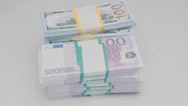 Stacks of bank bundles with dollars and euros rotating on white background.