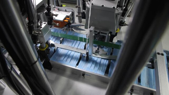 Automated machinery sticks elastic bands to surgical masks
